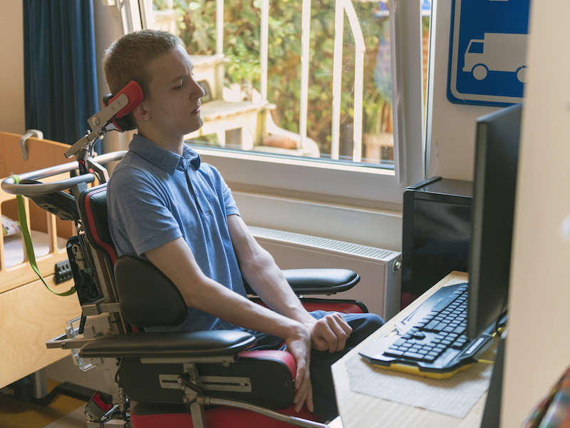 A young person with a disability uses a computer to fill out an absentee ballot